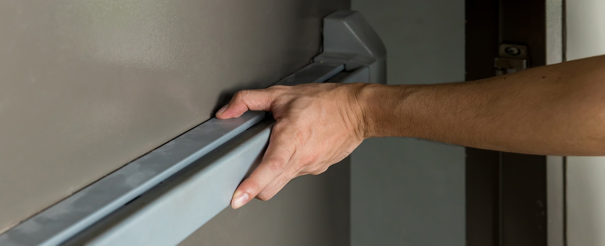 Hand is Opening the emergency fire exit door.